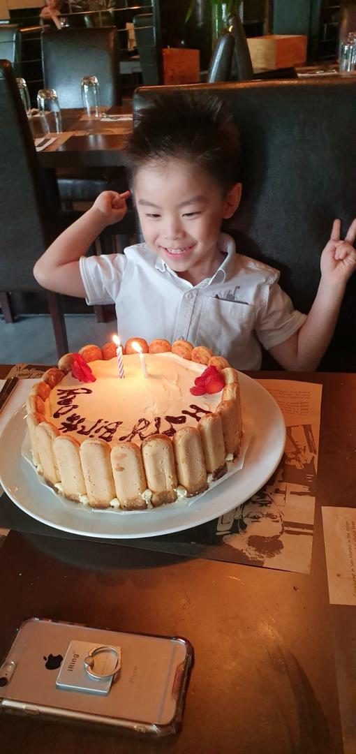 Little Wei Heng smiling at a strawberry birthday cake with candles