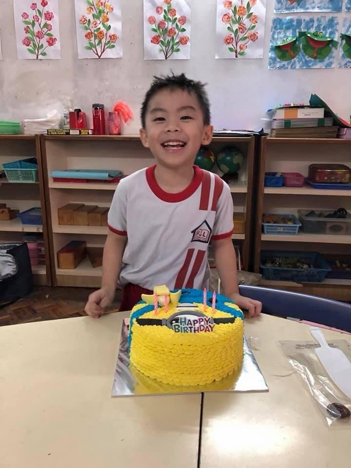 Wei Heng laughing behind a yellow Minion birthday cake